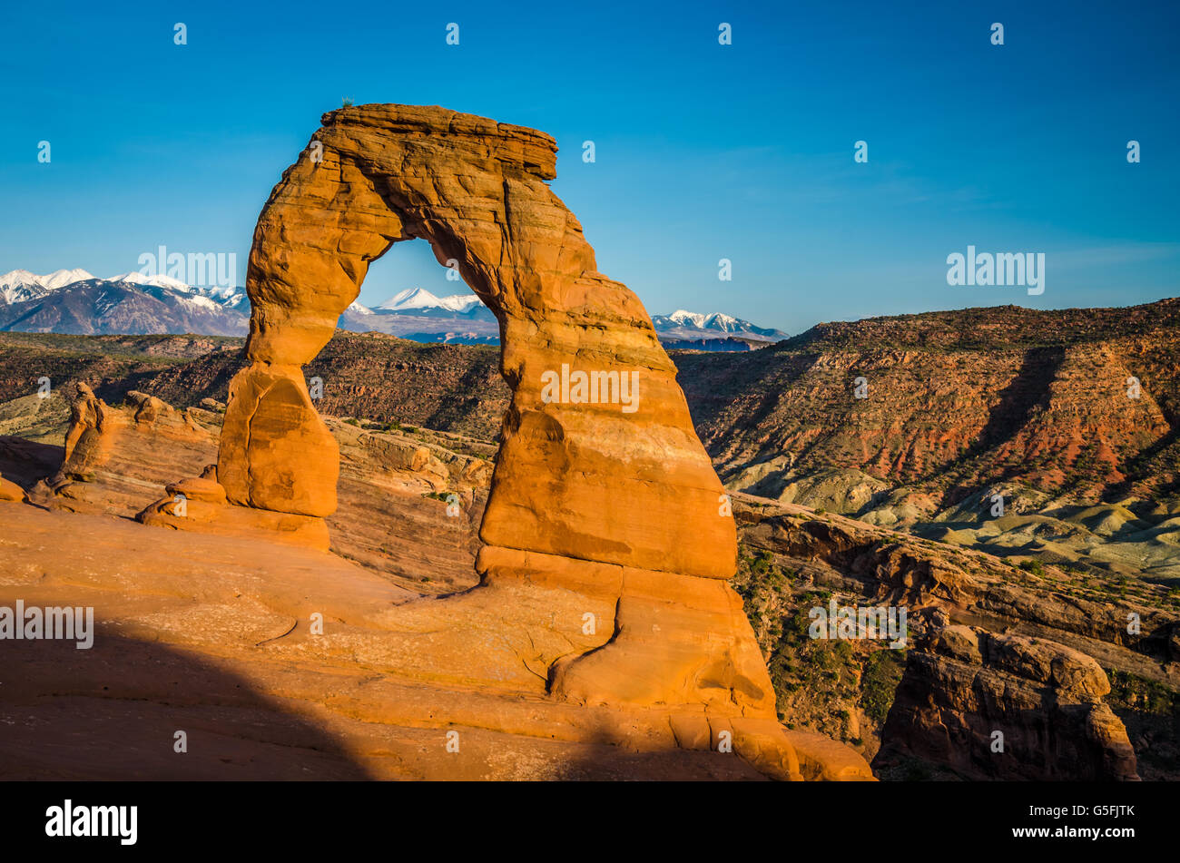 Catena montuosa innevata sullo sfondo sotto un arco nel Parco Nazionale Arches nello splendido Utah, in primavera. Natura mozzafiato e area turistica Foto Stock