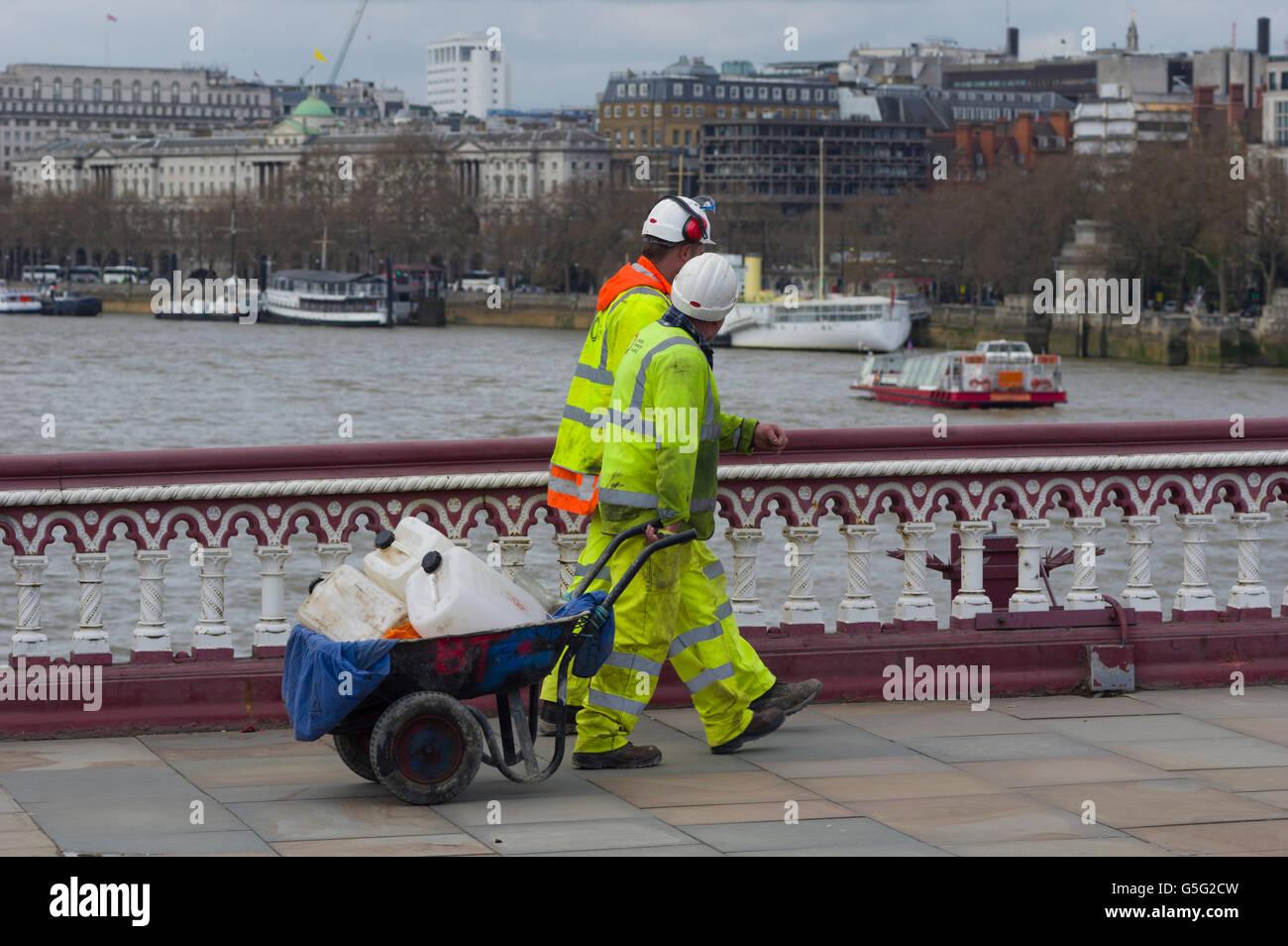 Due operai a elevata visibilità per capi di abbigliamento e copricapi rigidi attraversando un ponte sul fiume Tamigi a Londra, volti oscurati Foto Stock