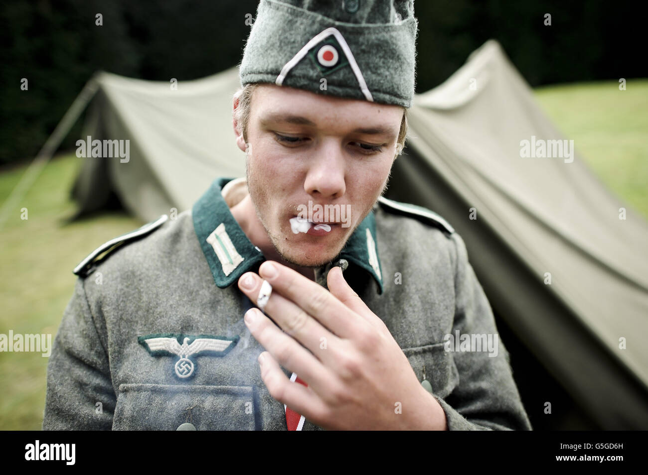 Foto. Kris Hodge 19, vestito da soldato tedesco di fanteria in prima classe privata, prende una resistenza della sua sigaretta roll-up al Weekend della seconda guerra mondiale a Castle Drogo in Devon. Foto Stock