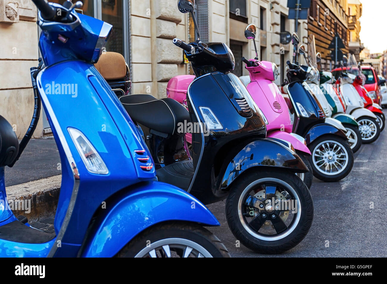 Alcuni multi-colore di scooter parcheggiato in una riga in corrispondenza del bordo della strada. Foto Stock