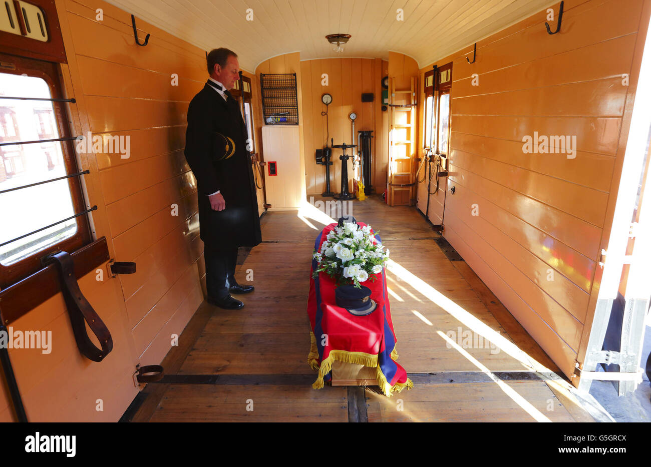 Il Maestro della Stazione David Middleton rende omaggio a Bernard Holden, fondatore della Bluebell Railway, mentre la sua bara viene portata al suo funerale in un furgone del freno sulla ferrovia a vapore Bluebell Line presso la stazione di Sheffield Park vicino a Lewes, East Sussex. Foto Stock