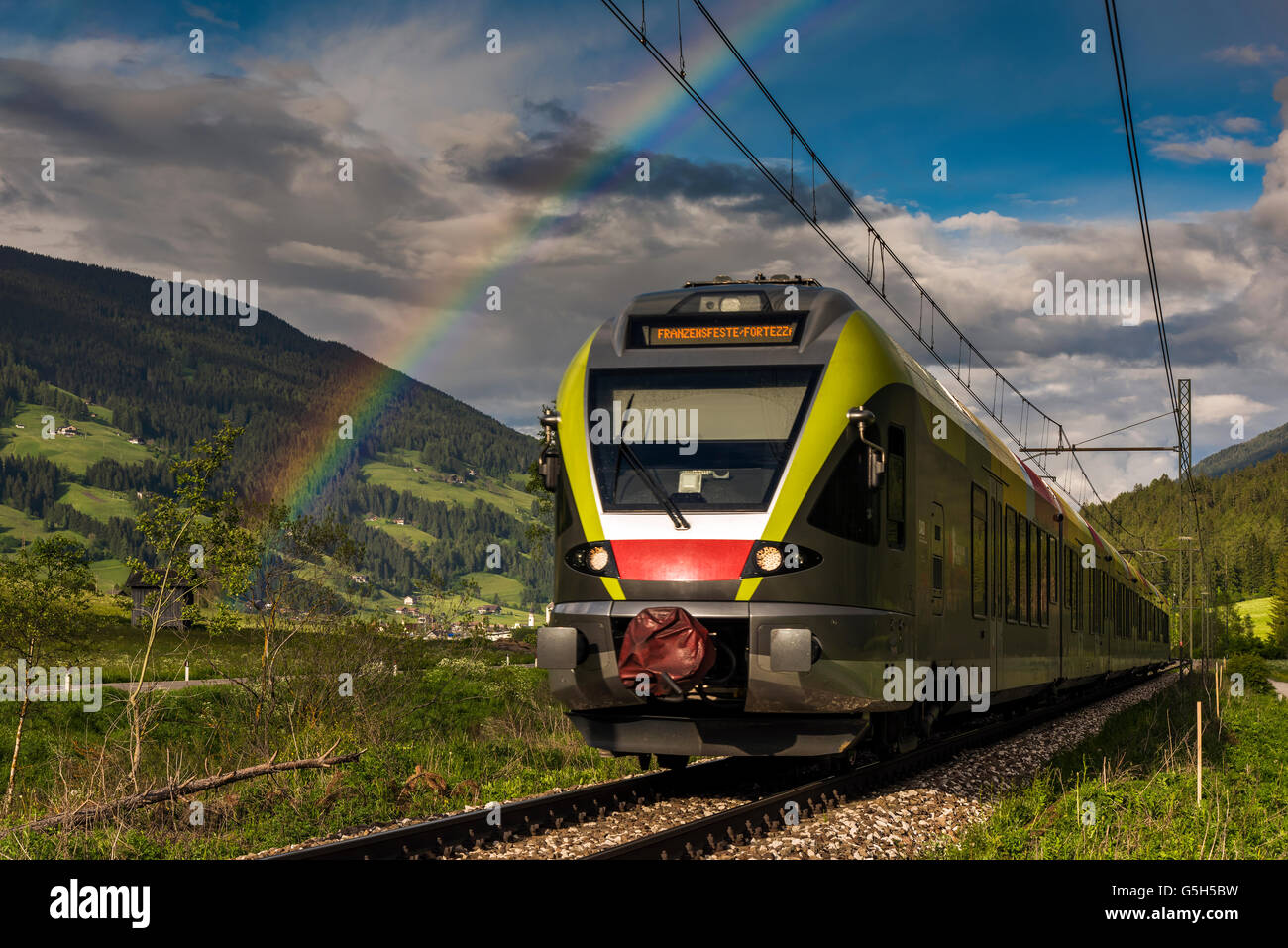 Paesaggio di montagna con il treno e rainbow in Val Pusteria o Val Pusteria, Alto Adige, Italia Foto Stock