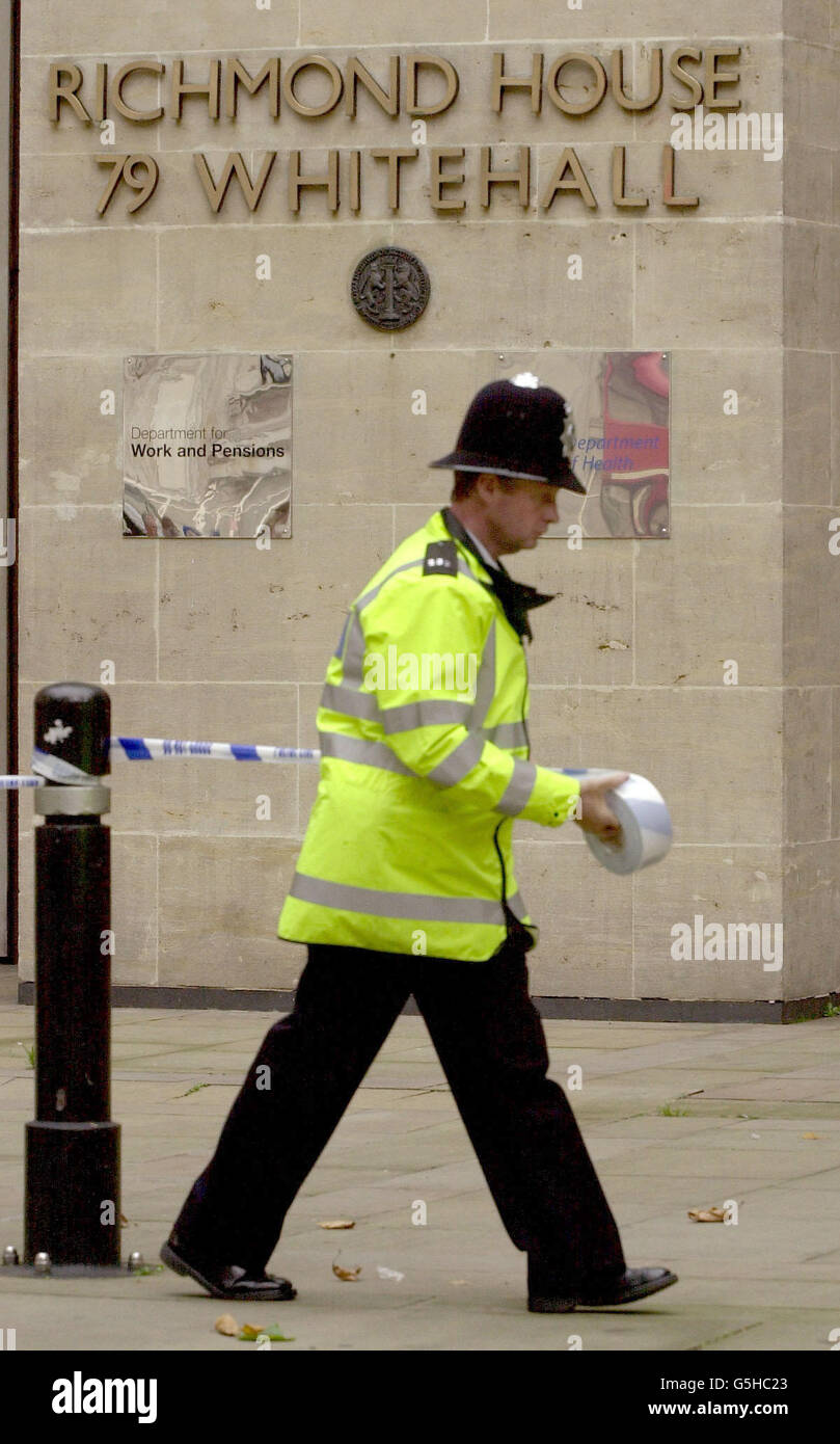 Un ufficiale di polizia sigilla l'ingresso principale del Dipartimento della Sanità nella Whitehall di Londra, dove i funzionari stavano indagando su un pacchetto supicous. *... Anche la vicina camera della Camera dei Comuni è stata chiusa brevemente a causa di un pacchetto sospetto nell'ufficio postale dedicato alla loro posta. Un'ora più tardi sono stati autorizzati a visitare le famose panchine verdi, ma la lobby dei deputati è rimasta chiusa. La sicurezza è stata intensificata intorno al Palazzo di Westminster in seguito agli attacchi terroristici del 11 settembre. Foto Stock