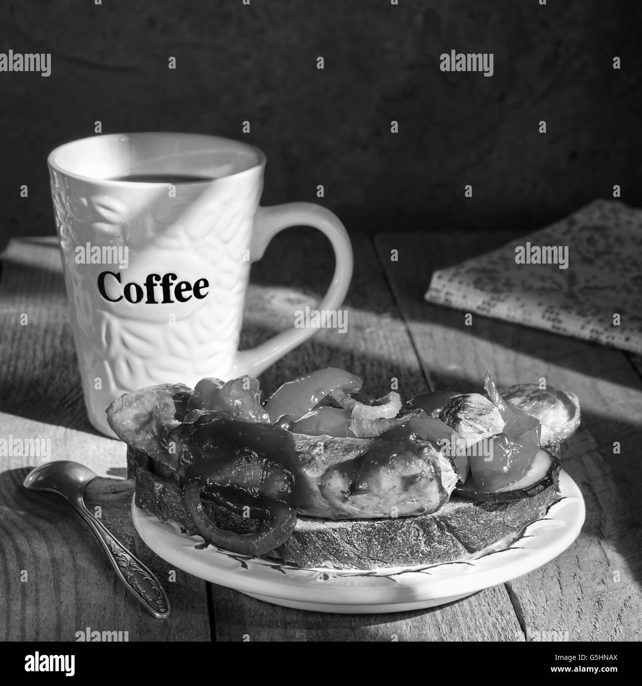 Sandwich con salsicce alla griglia su un piatto e tazza da caffè Foto Stock