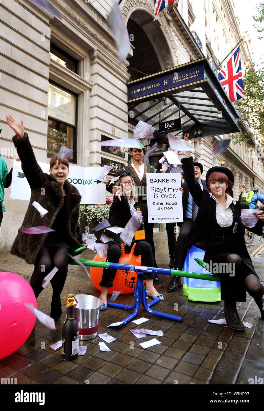 Un gruppo di manifestanti con denaro falso e bottiglie di champagne dimostra contro l'industria bancaria e i loro standard, al di fuori della conferenza annuale della British Bankers Association a Londra. Foto Stock