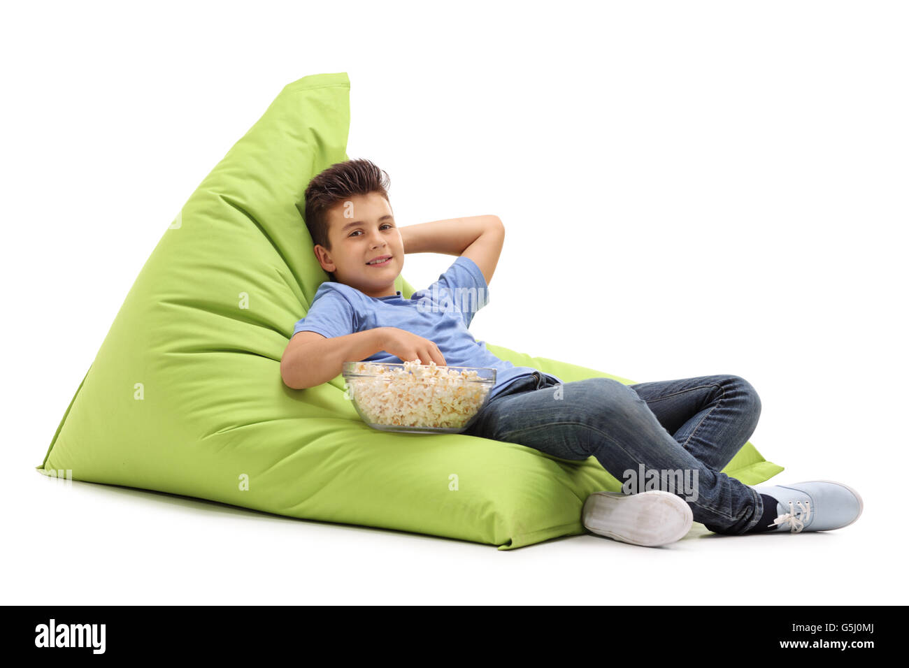Gioioso bambino seduto su una comoda beanbag verde e mangiare popcorn isolati su sfondo bianco Foto Stock