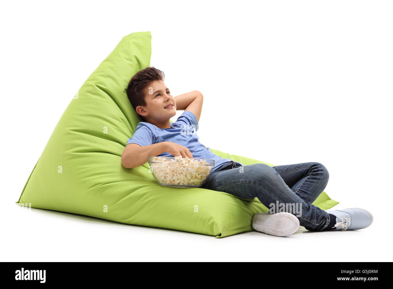 Malinconici little boy mangiare popcorn seduto su un verde beanbag isolati su sfondo bianco Foto Stock