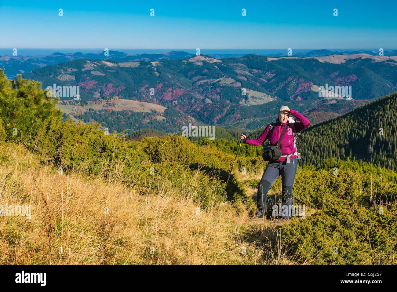 Donna di stare sul prato erboso nel paesaggio di montagna Foto Stock