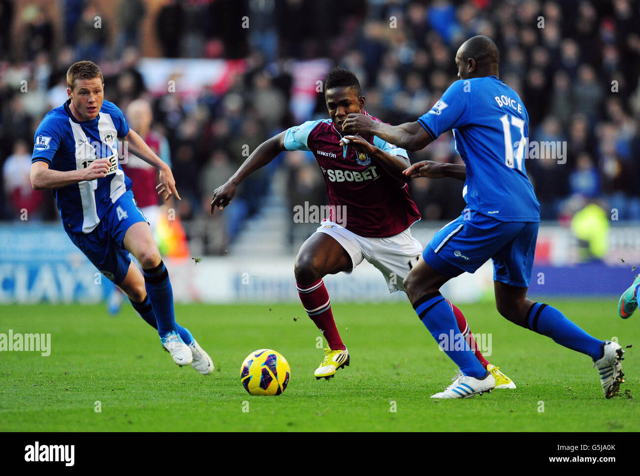 Il Modibo Maiga di West Ham United batte James McCarthy di Wigan Athletic (a sinistra) e Emmerson Boyce durante la partita della Barclays Premier League al DW Stadium di Wigan. Foto Stock