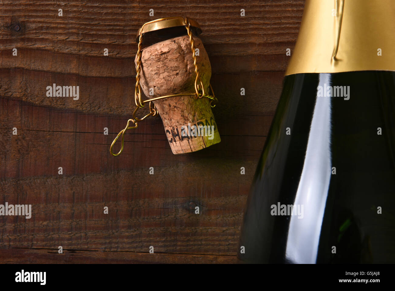 Vista aerea di una bottiglia di Champagne accanto a un tappo di sughero e la gabbia. Formato orizzontale su di un legno scuro sfondo, con copia spazio. Foto Stock