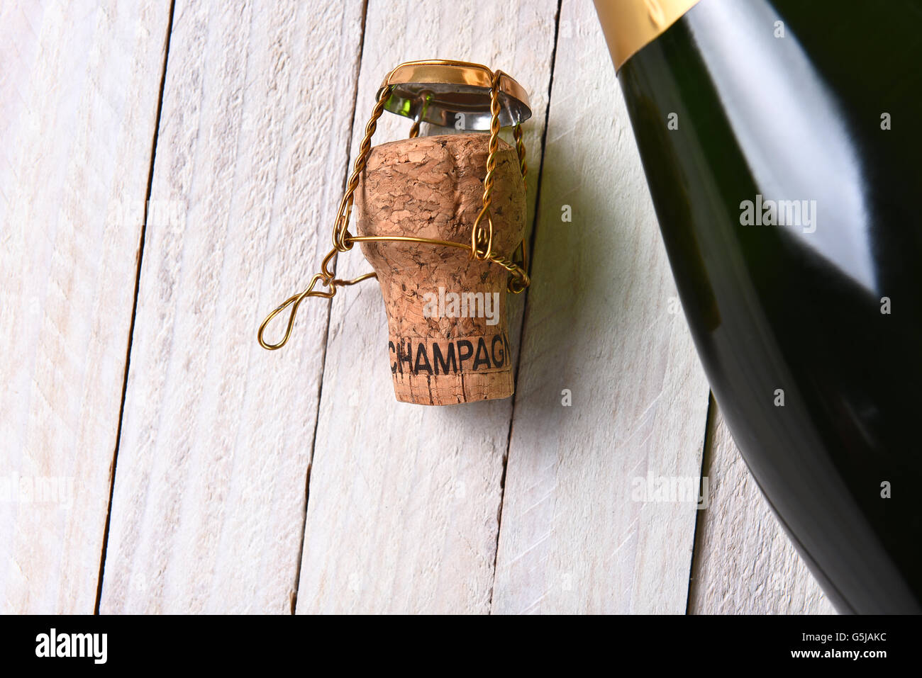 Vista superiore di una bottiglia di champagne accanto a un tappo di sughero in un rustico di legno bianco tavola. Formato orizzontale con copia spazio. Foto Stock
