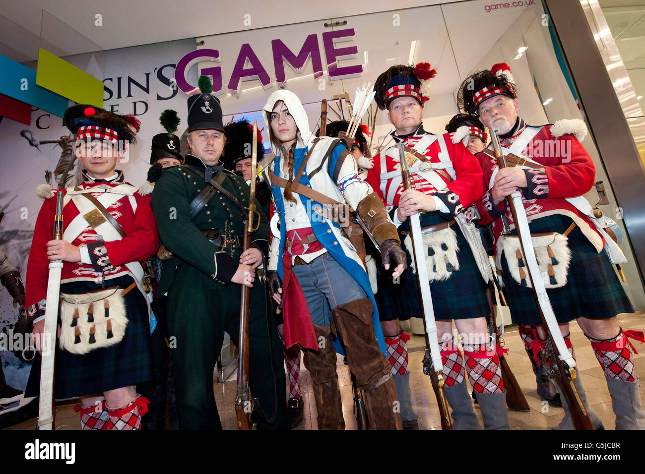 Laura Tolton, di Hockley, in costume come "The Assassin", (al centro) è circondato da Redcoats prima di acquistare una copia di Assassins Creed III presso il negozio più importante del GIOCO, Stratford a Londra, che ha aperto a mezzanotte, così i fan potrebbero ottenere una copia nel momento in cui il gioco è stato rilasciato. Foto Stock