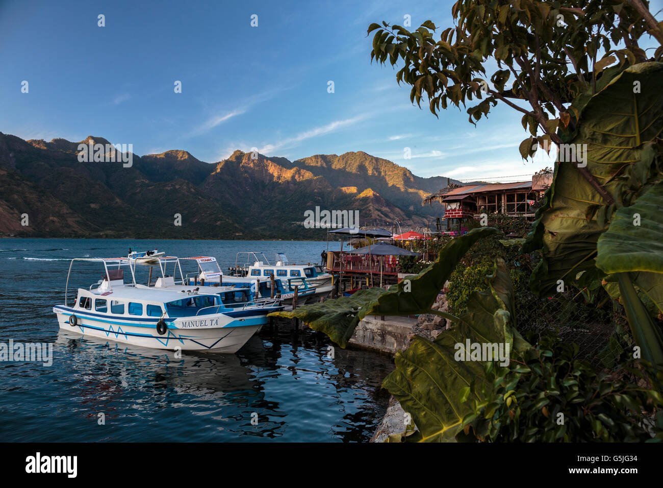 Tramonto dipinge le scogliere del cratere che forma il lago Atitlan in Guatemala meridionale. Con un taxi acqueo è ancorata a San Pedro La La Foto Stock