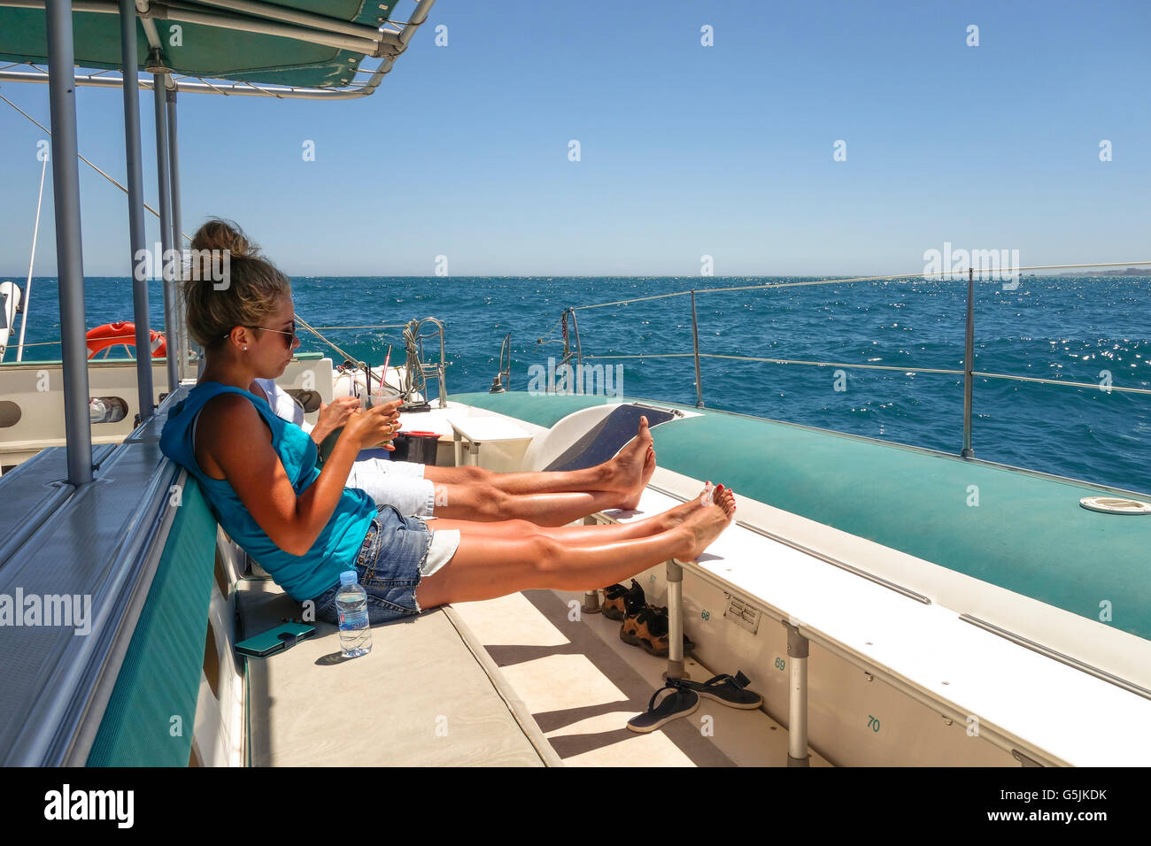 Coppia giovane sul catamarano, avente un drink sulla barca a vela tour, rilassarsi e godersi il sole, Malaga, Andalusia, Spagna. Foto Stock