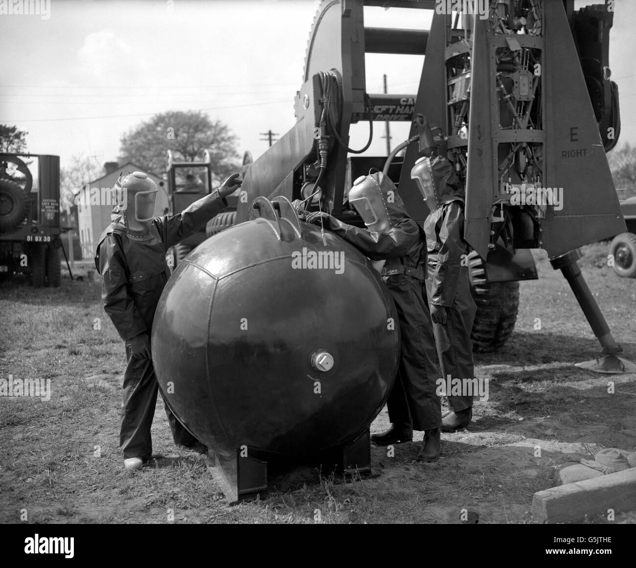 Tre membri del 47° reggimento d'armi guidato, l'artiglieria reale, indossano abiti protettivi mentre disalimentano un missile superficie-superficie. Dopo l'addestramento con l'arma corporale sviluppata dagli americani, si stanno preparando per la firma missilistica programmata, prima che il reggimento si unisca alle forze NATO del generale Norstad in Germania. (l-r) Lance Bombardier J Boyes, di Huddersfield, Gunner GA Ellis, di Plymouth, e Gunner GA Samways, di Kidderminster. Foto Stock