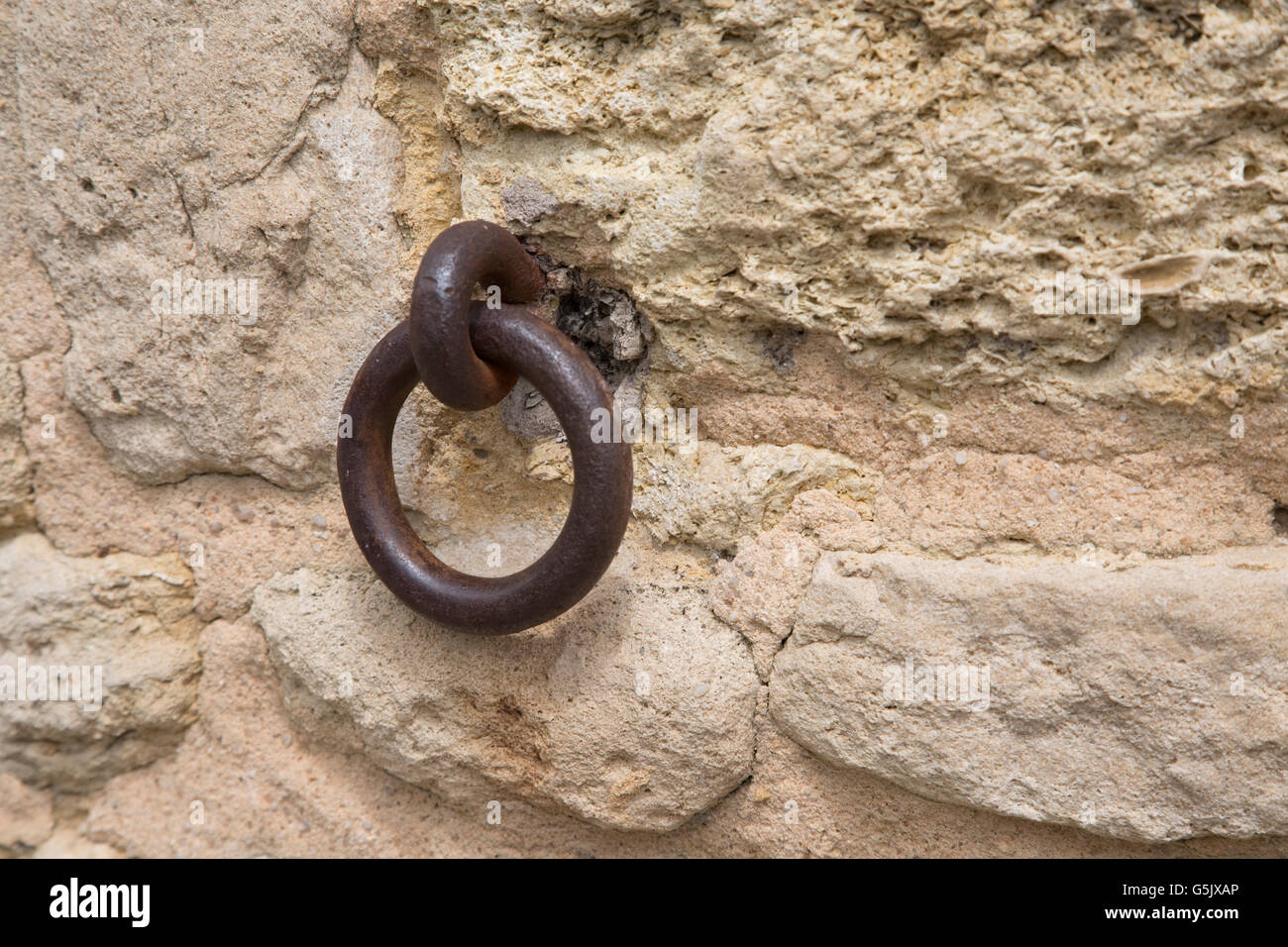 Il vecchio anello di ferro arrugginito utilizzati per i cavalli del sollevatore annegato nel muro di pietra Francia Foto Stock