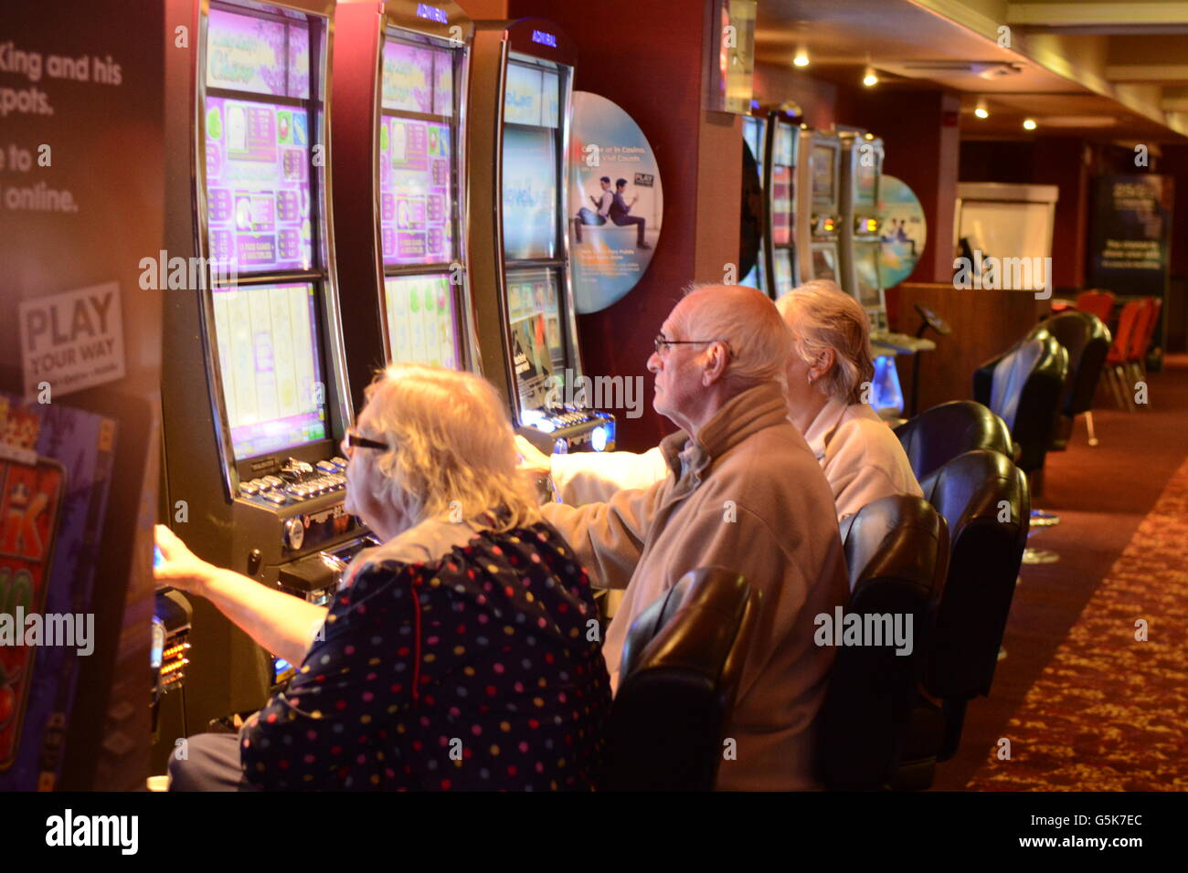 Persone giocare macchine per il gioco d'azzardo in un high street casino. Foto Stock