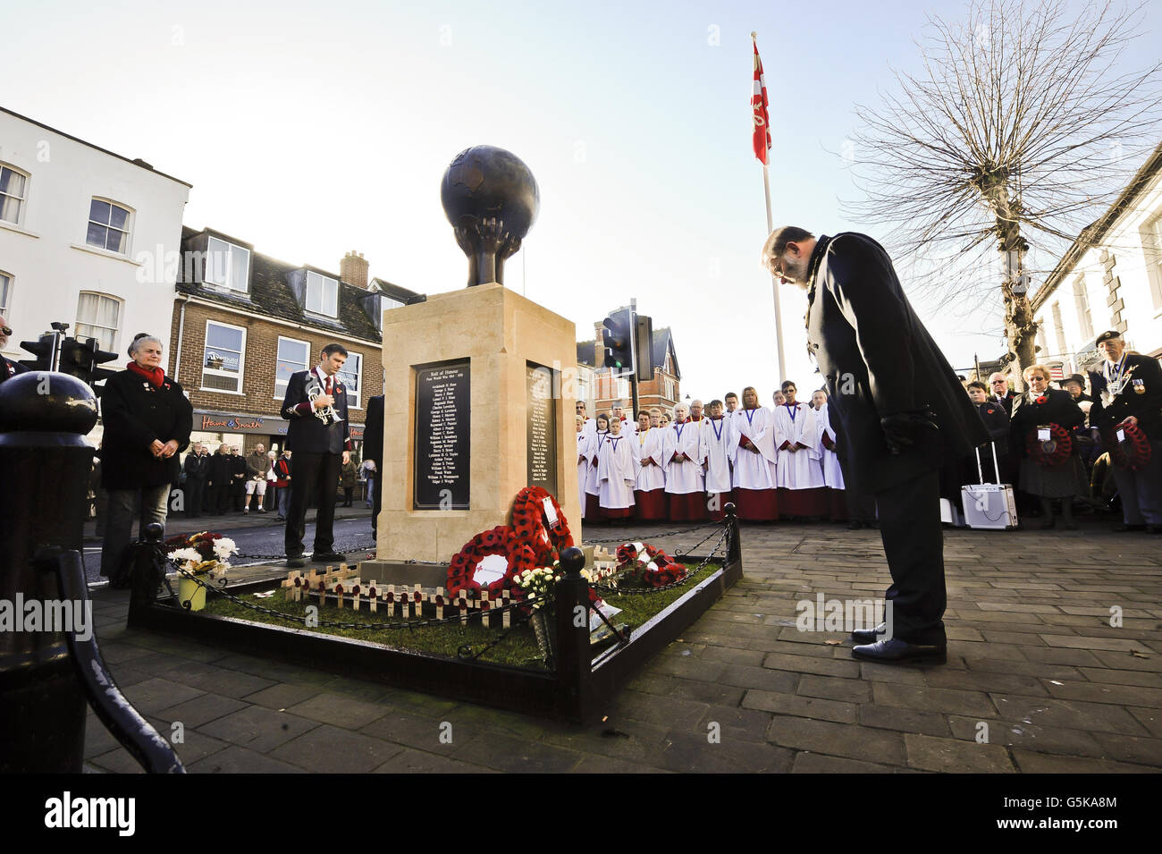 Vengono presi dei saluti e le corone del ricordo vengono poste sul memoriale di guerra nella High Street del Royal Wootton Bassett, dove un servizio di memoria e due minuti di silenzio viene osservato nella città del Wiltshire che è ora sinonoimosa con il rimpatrio del personale di servizio caduto. Foto Stock