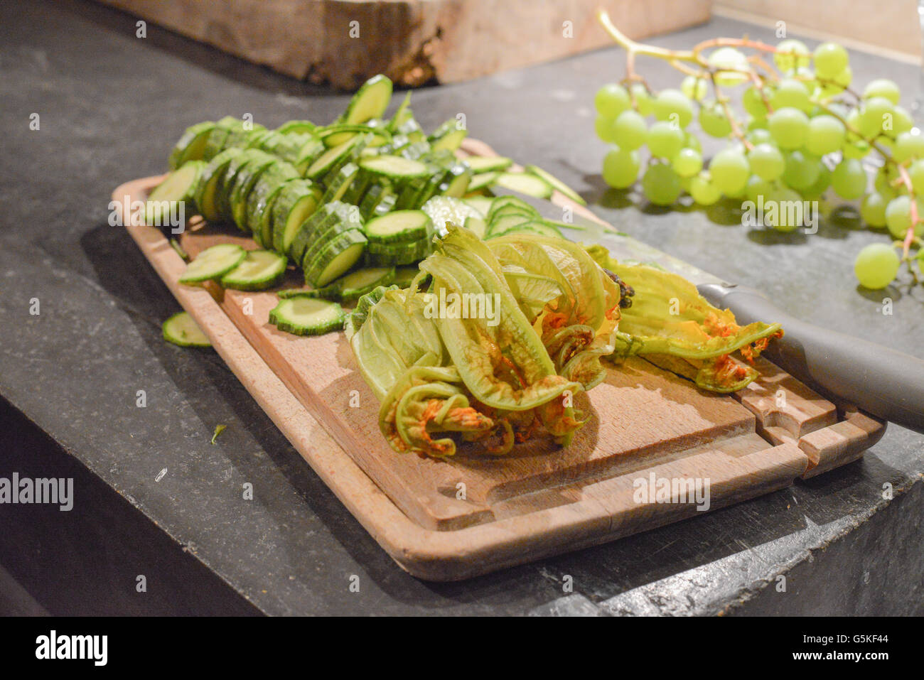 Pannello di legno con un fresco e le fette di zucchine e fiori di zucca. Foto Stock