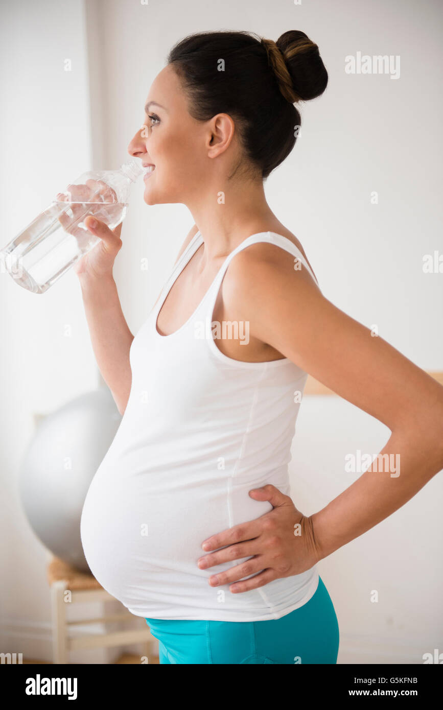 Incinta donna caucasici di bere acqua in bottiglia Foto Stock
