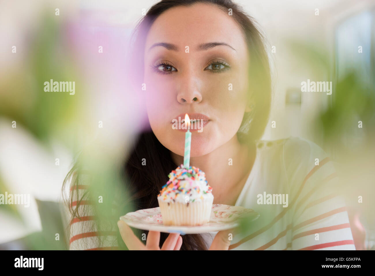 Donna di soffiaggio in fuori la candela di compleanno sul cupcake Foto Stock