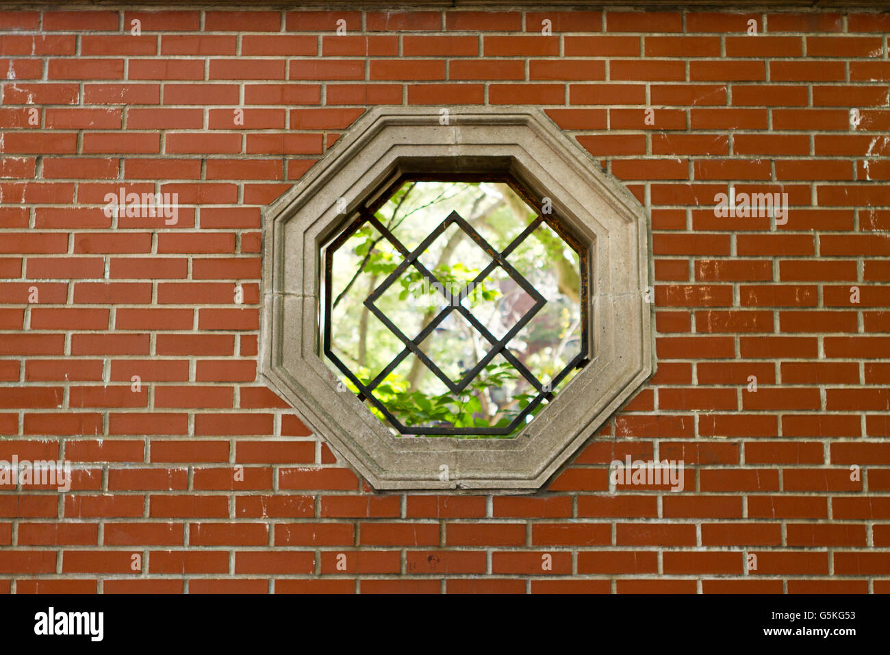 Forma geometrica finestra nel muro di mattoni in una New York City courtyard park Foto Stock