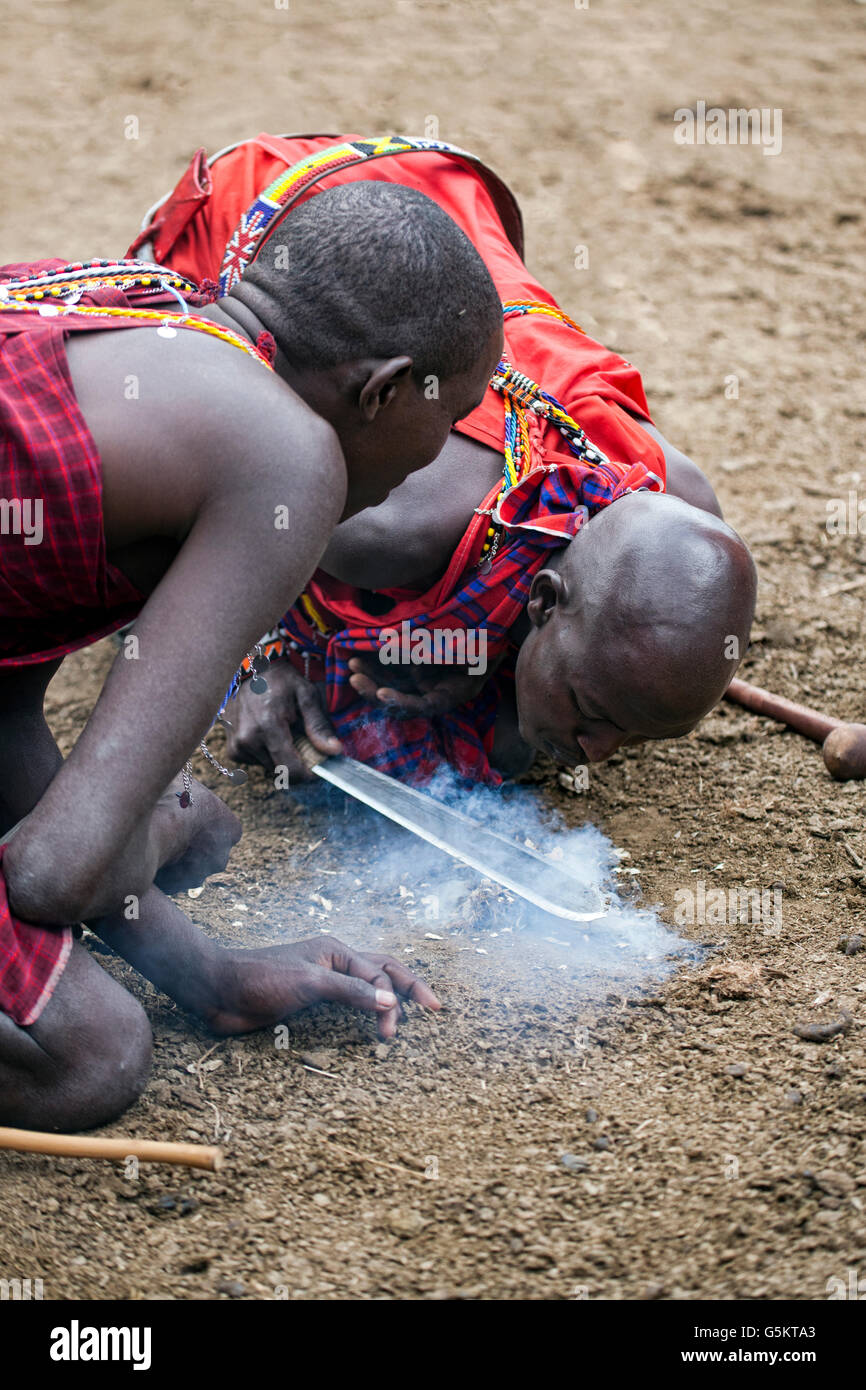 Un gruppo di giovani guerrieri Masai innescando un incendio nel villaggio dei masai in Kenya, Africa. Foto Stock