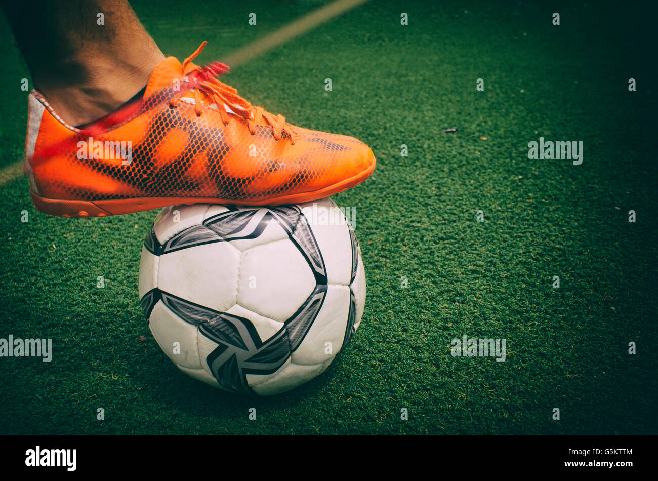 Fotografia di un piede e un pallone da calcio in erba Foto Stock