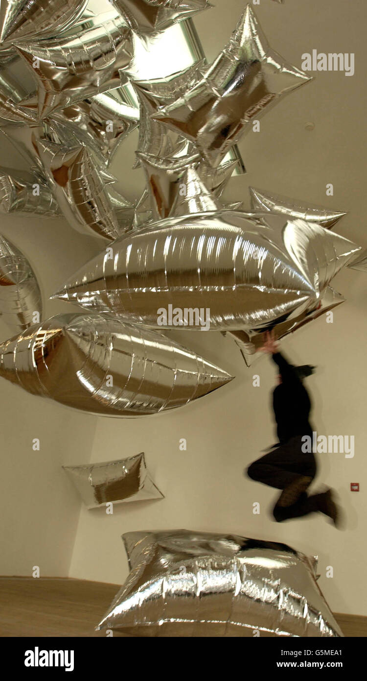 Un visitatore gode del contatto con Silver Clouds, un'opera del 1966, dell'artista americano Andy Warhol in mostra in un retropettivo del suo lavoro al Tate Modern sulla South Bank di Londra. La mostra si apre al pubblico il 7 febbraio. Foto Stock