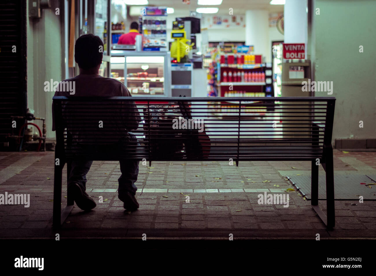 Uomo seduto sul banco della città di notte Foto Stock