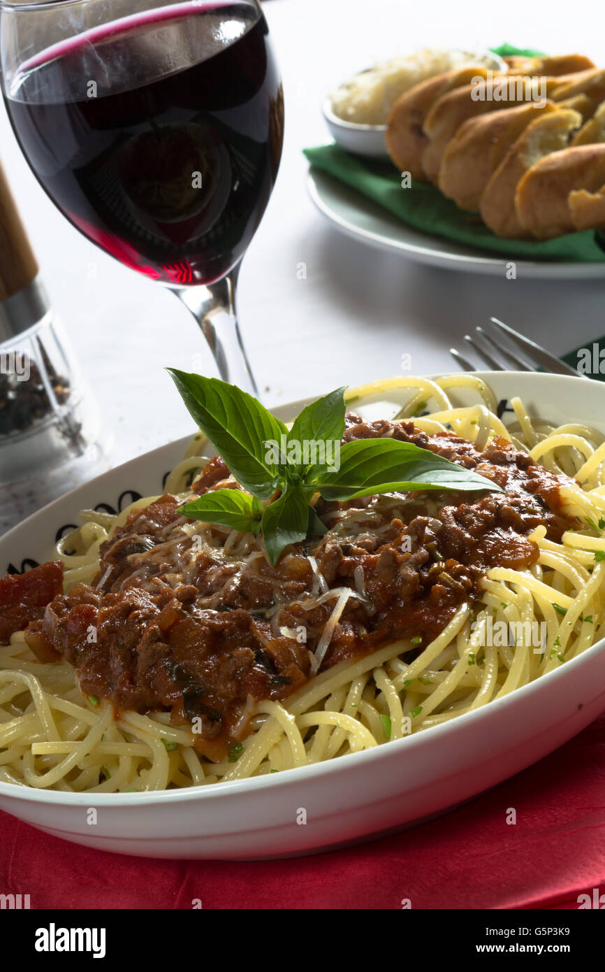Italiano tradizionale piatto di spaghetti alla bolognese/bolognese servita con pane all'Aglio/Baguette e parmigiano grattugiato. Foto Stock