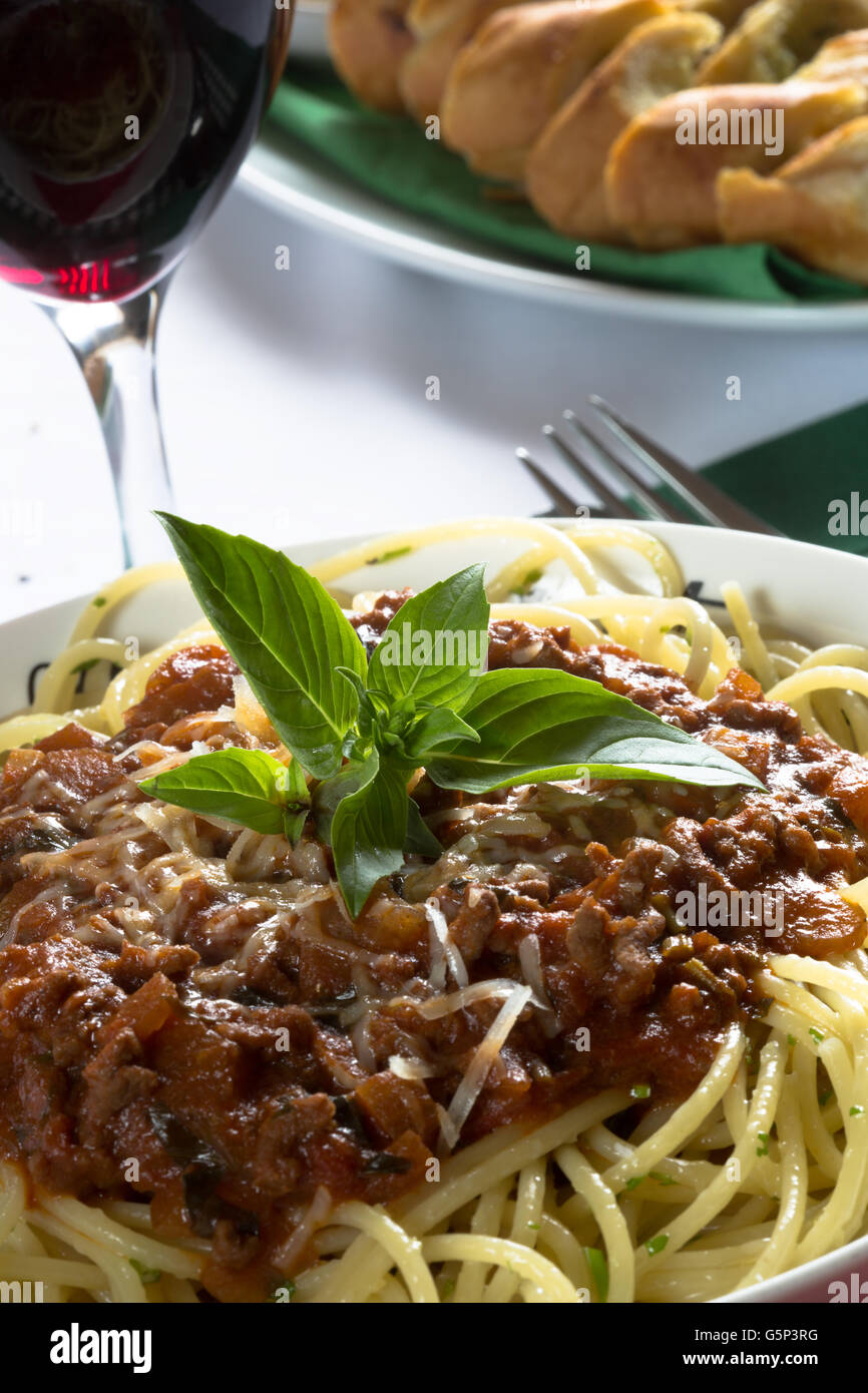 Italiano tradizionale piatto di spaghetti alla bolognese/bolognese servita con pane all'Aglio/Baguette e parmigiano grattugiato. Foto Stock