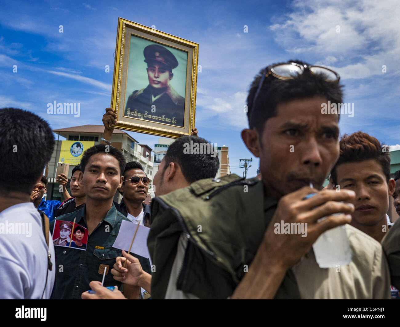 Mahachai, Samut Sakhon, Thailandia. Il 23 giugno, 2016. Lavoratori birmani immigrati attendere per Aung San Kyii per arrivare a Samut Sakhon, una provincia a sud di Bangkok. Decine di migliaia di lavoratori birmani immigrati, la maggior parte degli impiegati nella pesca tailandese industria, vivere in Samut Sakhon. Aung San Suu Kyi, il ministro degli Affari Esteri e consigliere di Stato per il governo di Myanmar (un ruolo simile a quello del Primo Ministro o di un capo di governo), è in visita di stato in Tailandia. Anche se lei e il suo partito ha vinto le elezioni 2015 da una frana, ella è costituzionalmente vietata dal divenire il Presidente a causa di un cl Foto Stock