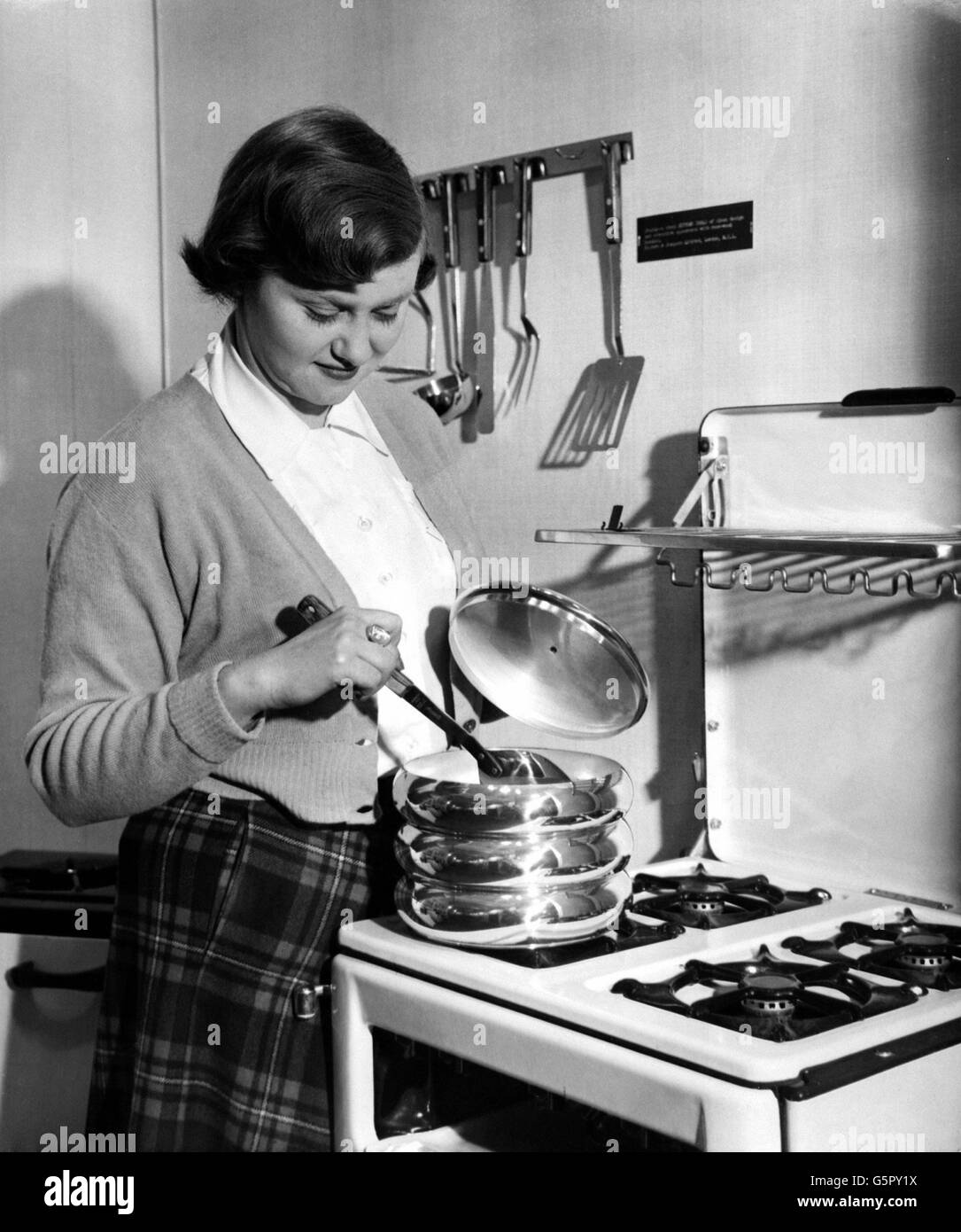 La sig.ra Daphne Sole del Regent's Park ispeziona un set di padelle di alluminio filato in una mostra di apparecchiature domestiche sponsorizzata dal Council of Industrial Design presso la Murray House Exhibiton Hall di Londra. Foto Stock