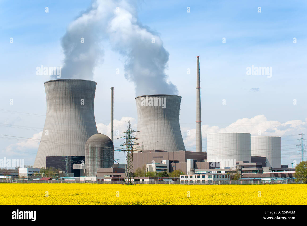 Energia nucleare il concetto di energia - Centrale nucleare con campo giallo e Big Blue Clouds. Impianto di energia nucleare in Germania Foto Stock