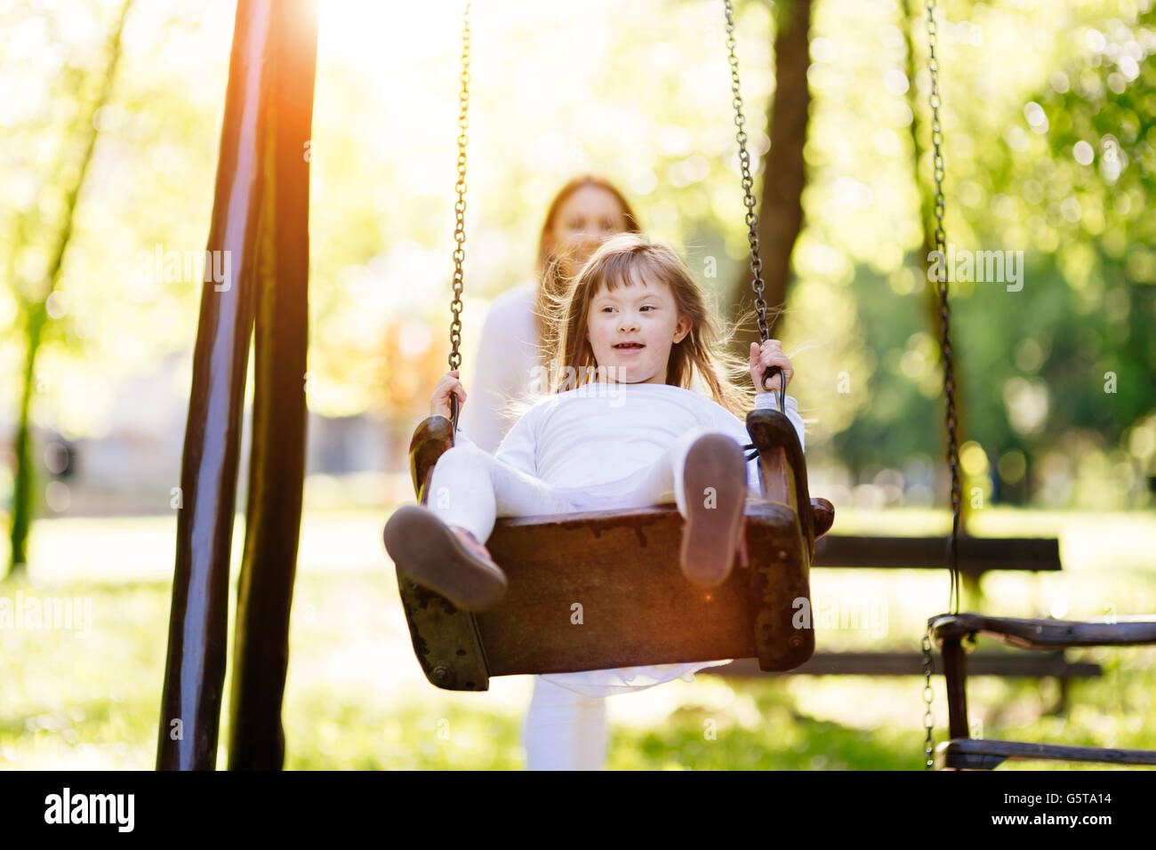Bambino disabile godendo lo swing all aperto con la sorella Foto Stock