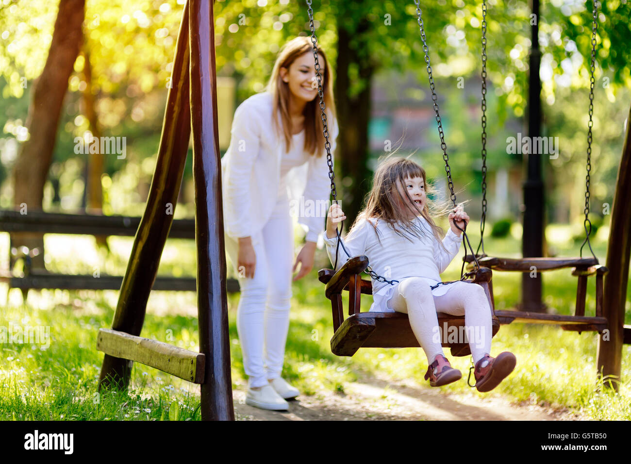 Bambino con handicap godendo lo swing all aperto con la sorella Foto Stock