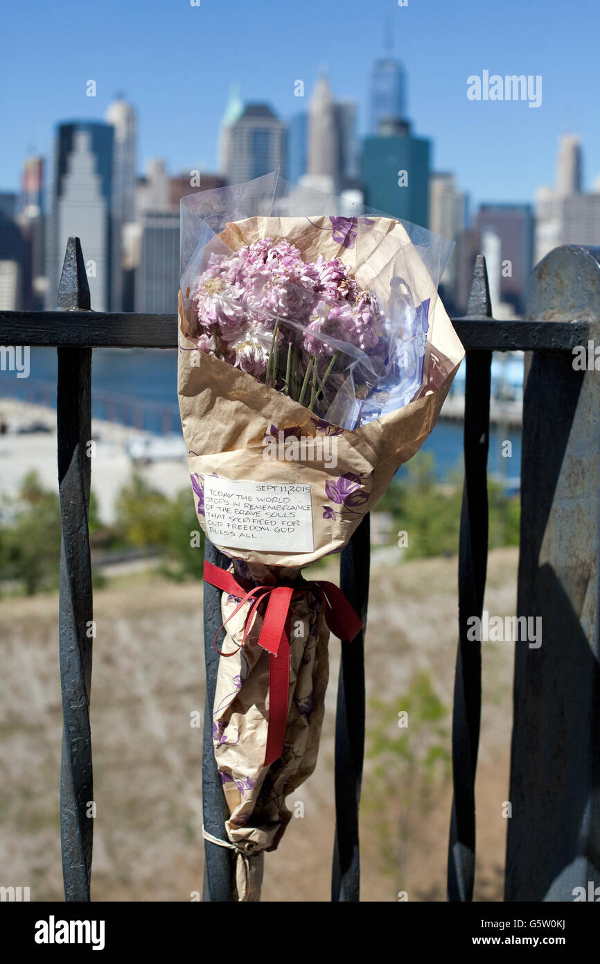 Fiori su una recinzione in commemorazione dell'11 settembre a New York, sullo sfondo è possibile vedere il nuovo World Trade Center. Foto Stock