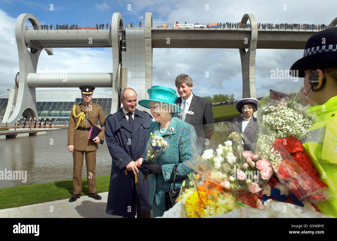 Una donna di polizia conserva un mazzo di fiori donati alla Regina dai wellwishers, mentre lei tournée e apre ufficialmente il sito della serratura della ruota Falkirk in Scozia, come parte delle continue celebrazioni del Giubileo d'Oro. Foto Stock