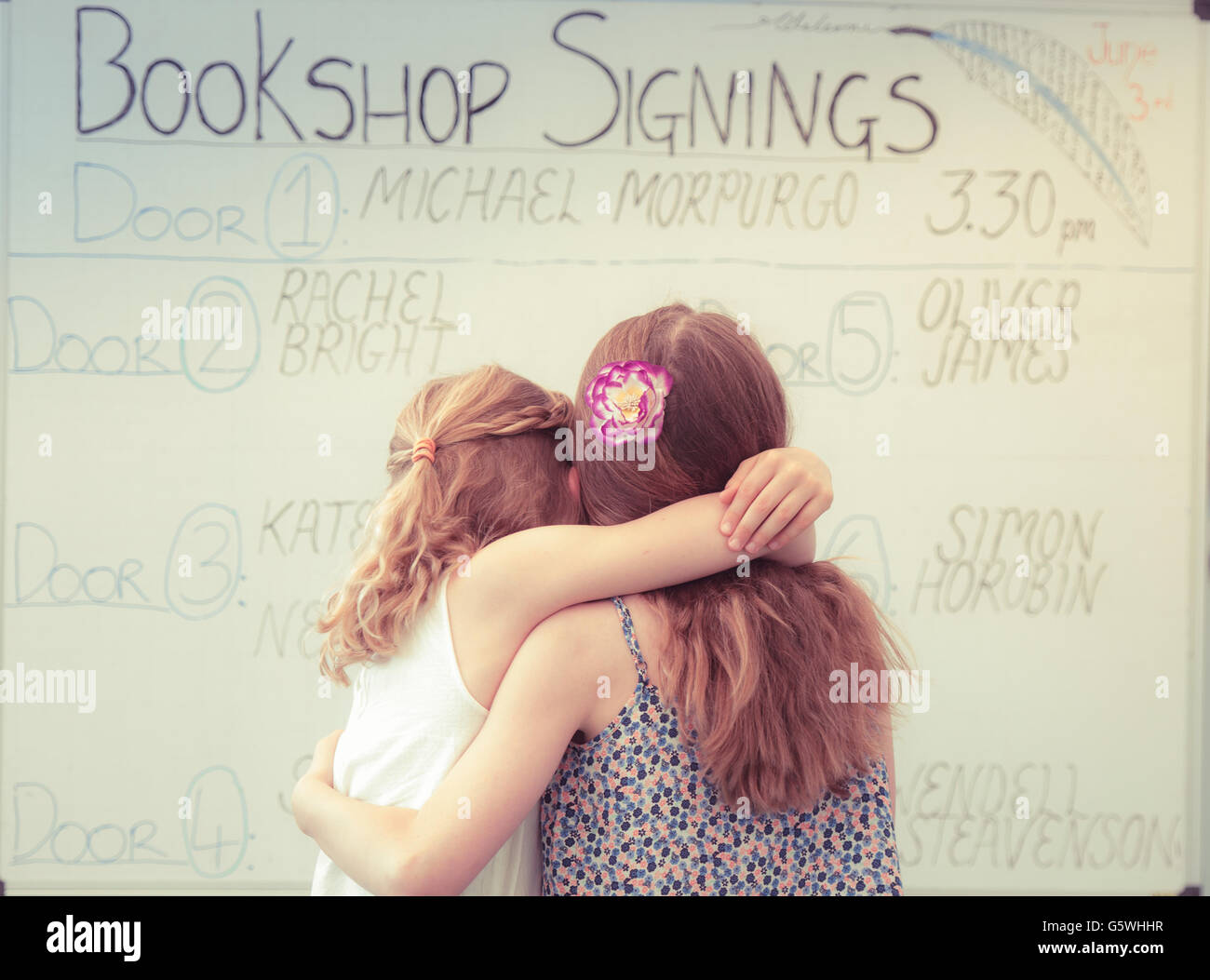 Vista posteriore di due ragazze alla ricerca presso il bookshop libro firma calendario presso la Hay Festival della letteratura e delle arti, Hay on Wye, Powys, Wales UK, Giugno 03 2016 Foto Stock