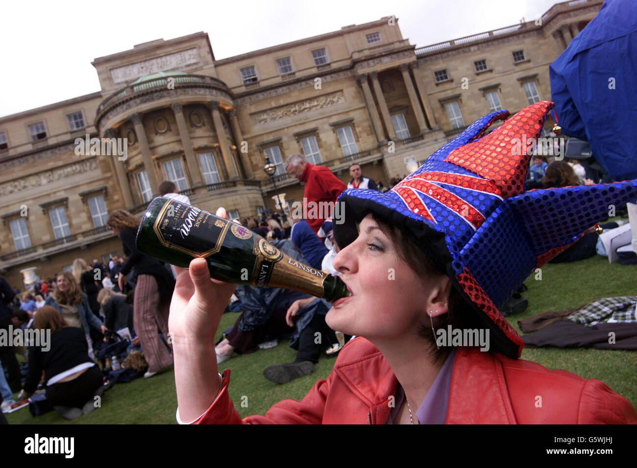 Un membro del pubblico gode di champagne gratuito, mentre attende il concerto rock del Golden Jubilee nei giardini di Buckingham Palace. * lo spettacolare Giubileo sarà lanciato con il chitarrista della regina Brian May che eseguirà l'inno nazionale dal tetto del palazzo. Foto Stock