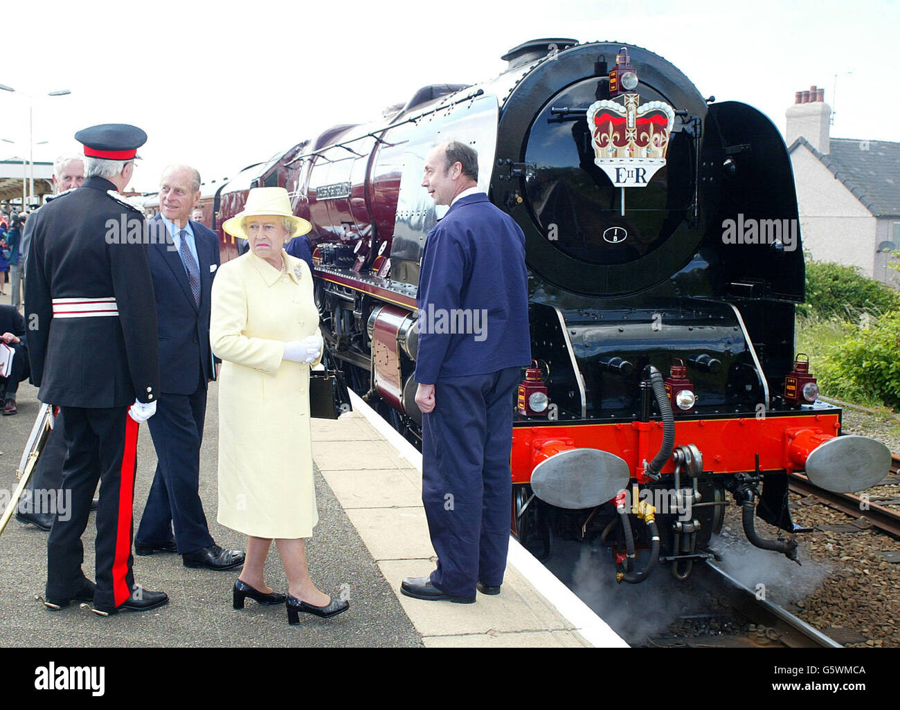 Sua Maestà la Regina si gira per vedere un treno di passaggio mentre vede la Duchessa di Sutherland locomotiva a vapore alla stazione ferroviaria di Llandudno Junction dopo la sua visita al Galles del Nord. Foto Stock