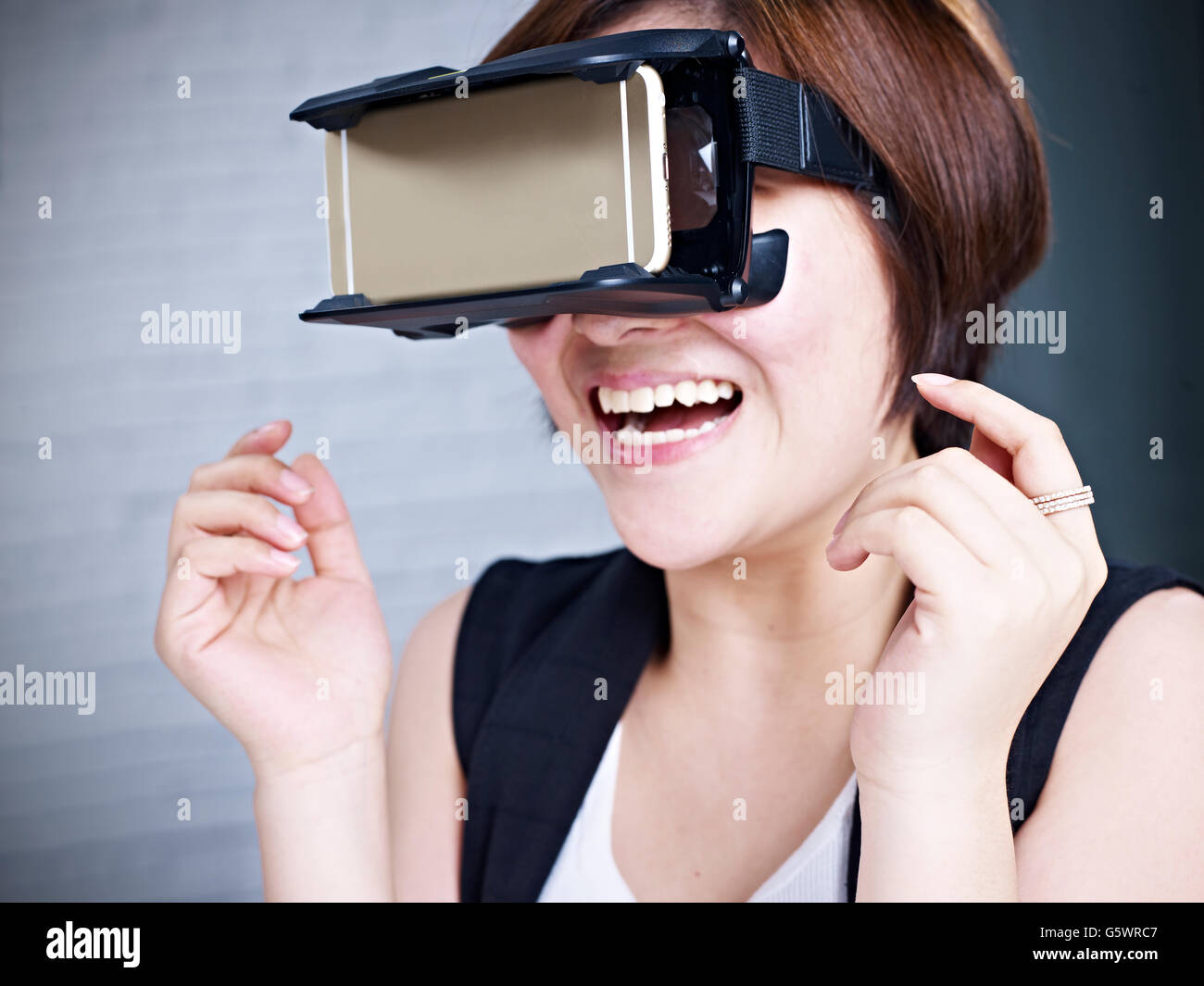Giovane donna asiatica vivendo la realtà virtuale con testa montata su occhiali VR. Foto Stock