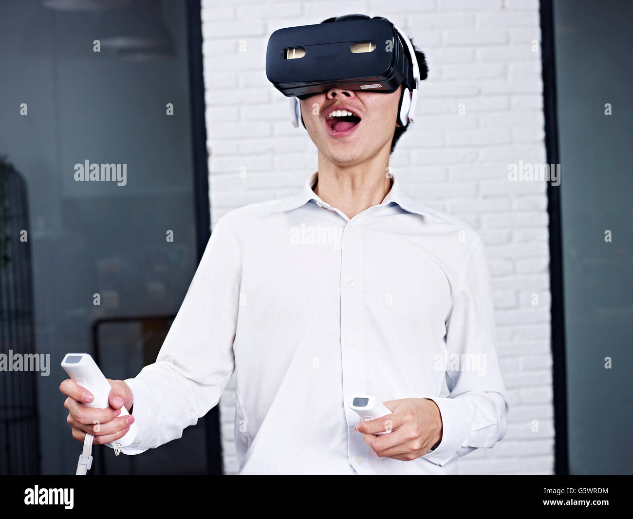 Giovane uomo asiatico gioco di realtà virtuale (VR) occhiale. Foto Stock