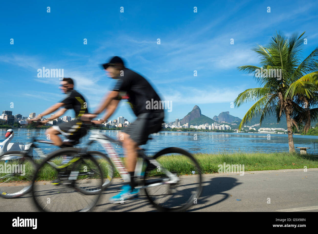 RIO DE JANEIRO - Gennaio 31, 2016: I ciclisti passano in motion blur contro una calma vista la mattina di Lagoa Rodrigo de Freitas. Foto Stock