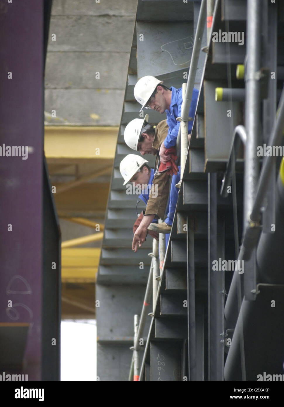 I lavoratori del cantiere navale Alstom Chantiers de l'Atlantique di Saint Nazaire, Bretagna, Francia, osservano come la cerimonia di posa della chiglia si svolge sulla Regina Maria 2. * la cerimonia ha segnato l'inizio simbolico della costruzione della nave lunga 1.132 piedi che si torreggierà a 200 piedi sopra la linea d'acqua che farà il suo viaggio inaugurale da Southampton a Fort Lauderdale il 14 gennaio 2004. Foto Stock