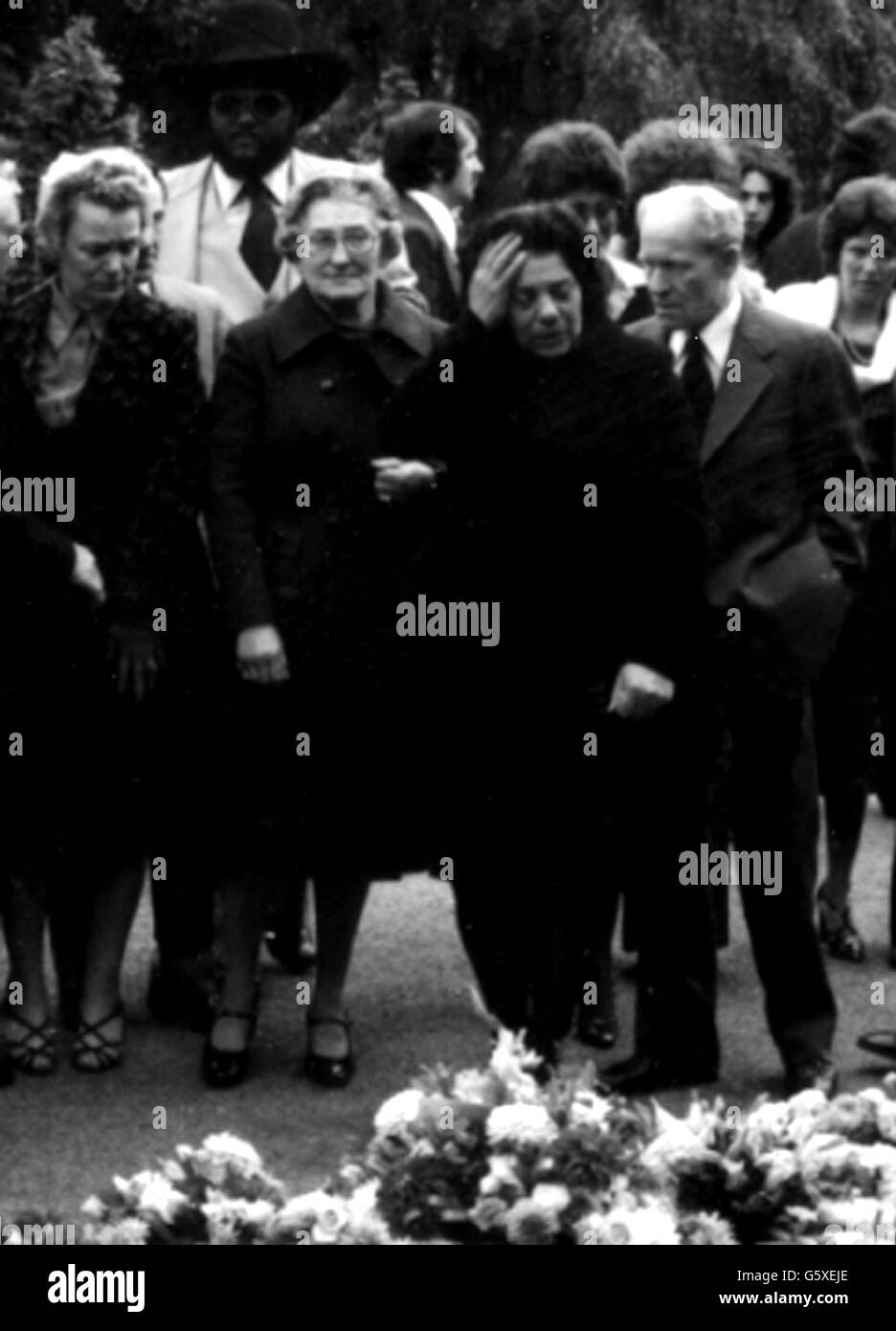 I membri della famiglia della pop star Marc Bolan stanno piangendo intorno agli omaggi floreali quando hanno partecipato al suo funerale al crematorio Golders Green. Dietro (a sinistra) c'è Richard Jones, fratello della fidanzata di Bolan Gloria Jones. Foto Stock