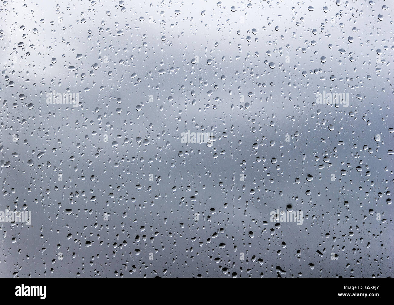 Gocce di pioggia sulla finestra di nuvole mosse in background Foto Stock