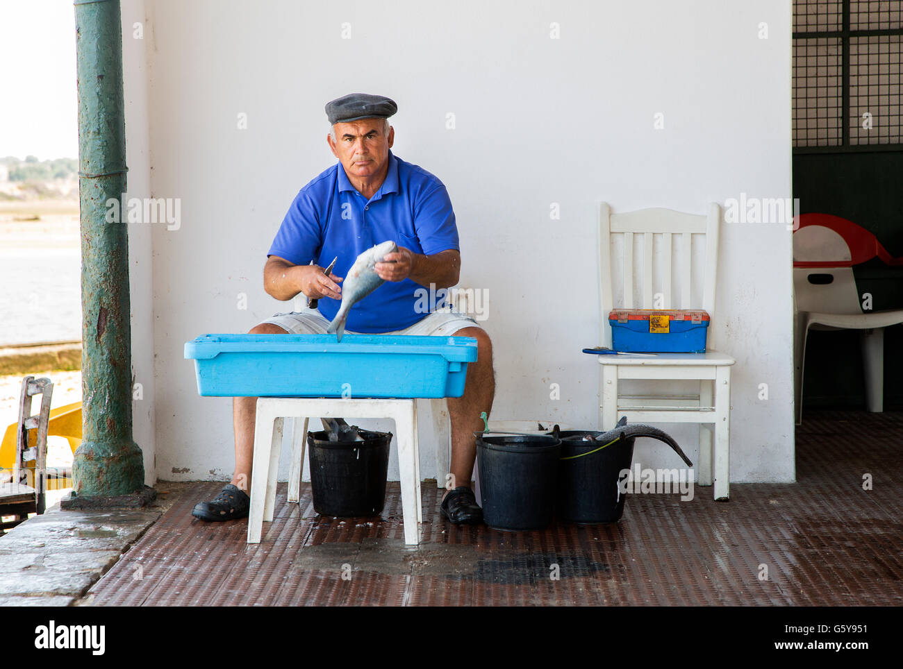 Pescatore locale pulizia del pesce sulla banchina nel piccolo villaggio di pescatori di Alvor, nella regione di Algarve Portogallo Foto Stock