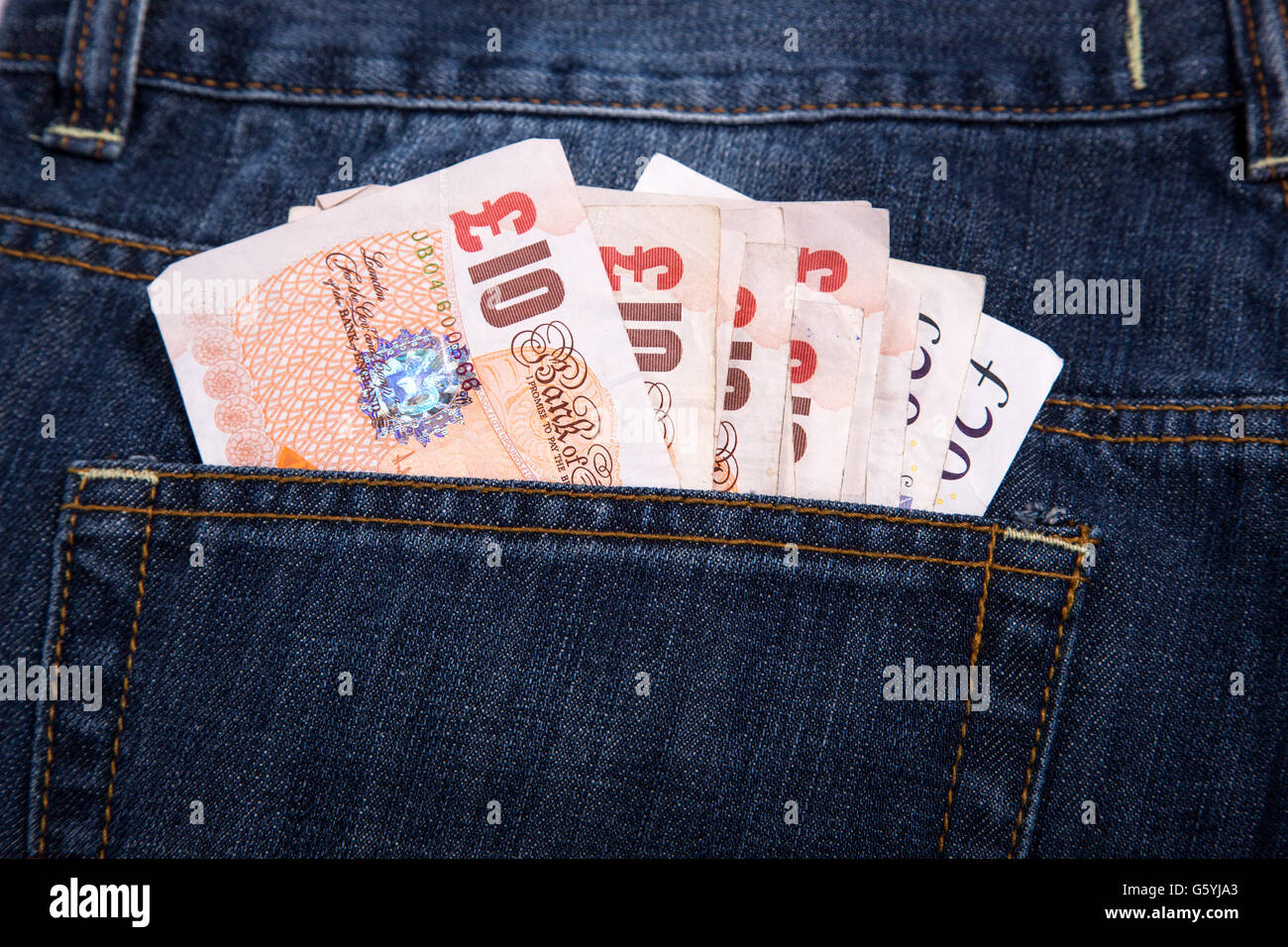 Valuta Sterlina soldi in tasca dei jeans Foto Stock
